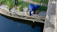 John starts to retrieve a fallen flask lid